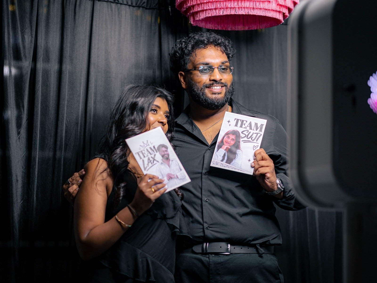 The couple holding their printed photo strips