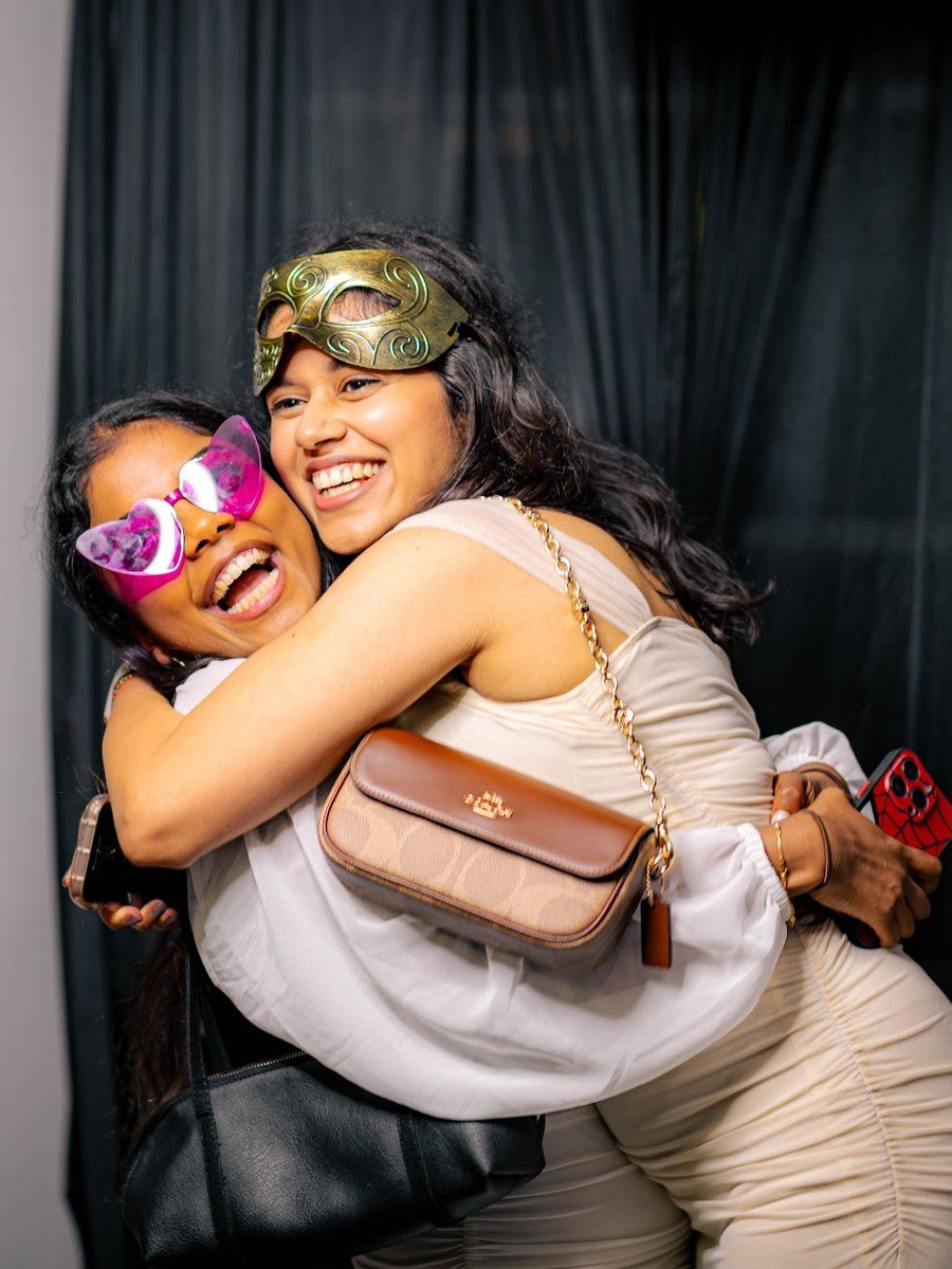 Guests hugging and laughing with props at the Manjal photo booth